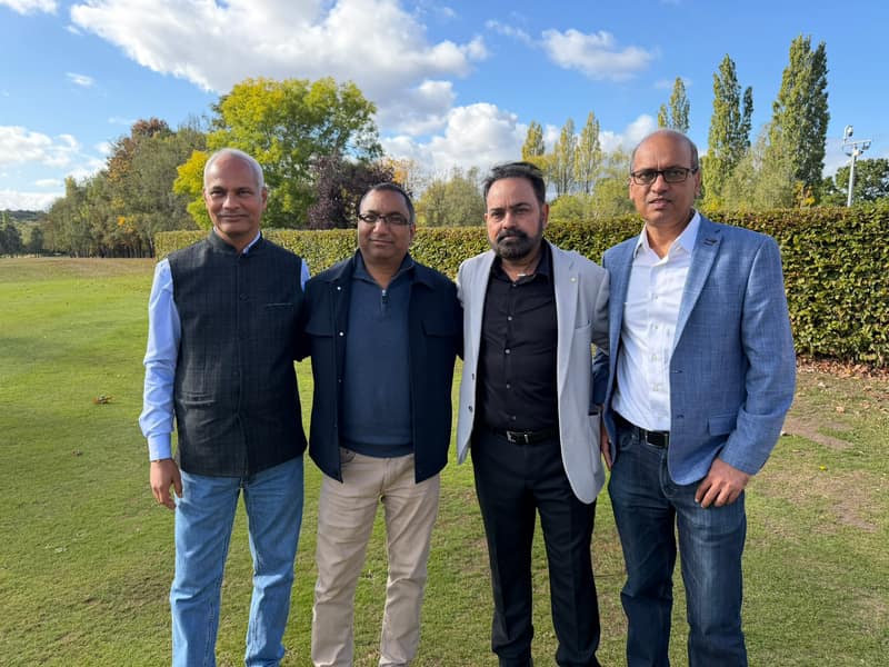 Four alumni standing together on the lawn