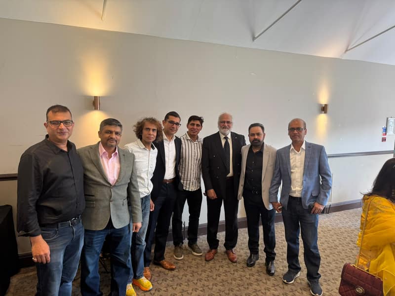 Eight alumni posing together indoors